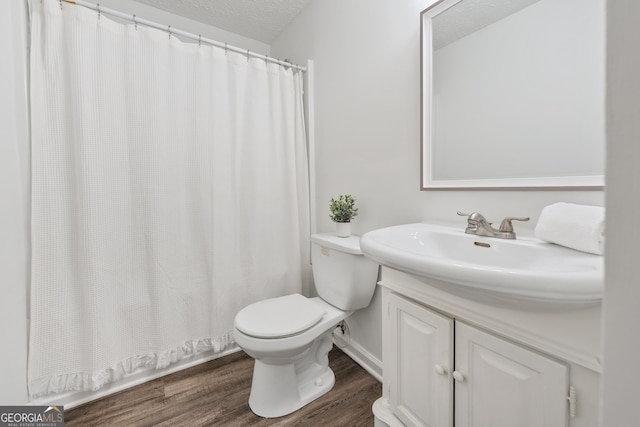 bathroom with a shower with shower curtain, toilet, vanity, wood finished floors, and a textured ceiling