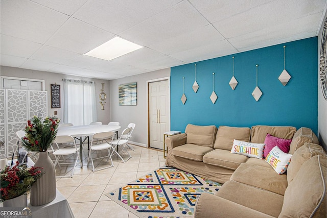 tiled living room featuring baseboards and a paneled ceiling