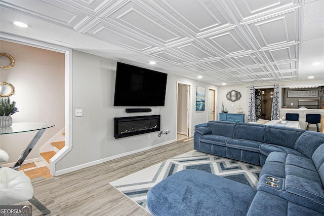 living area with wood finished floors, recessed lighting, baseboards, and an ornate ceiling