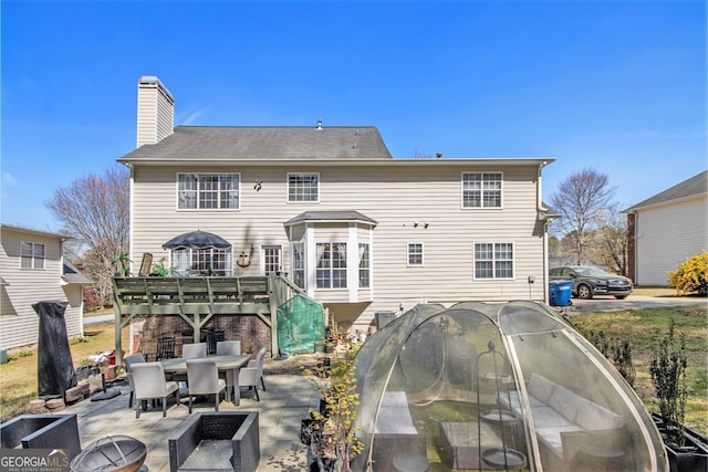 back of house with a patio, a chimney, and outdoor dining space
