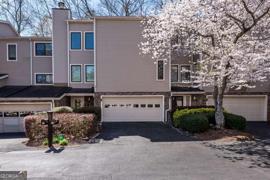58 Basswood Cir Unit 29, Atlanta, GA 30328 - townhome / multi-family property featuring driveway, an attached garage, a chimney, and stone siding