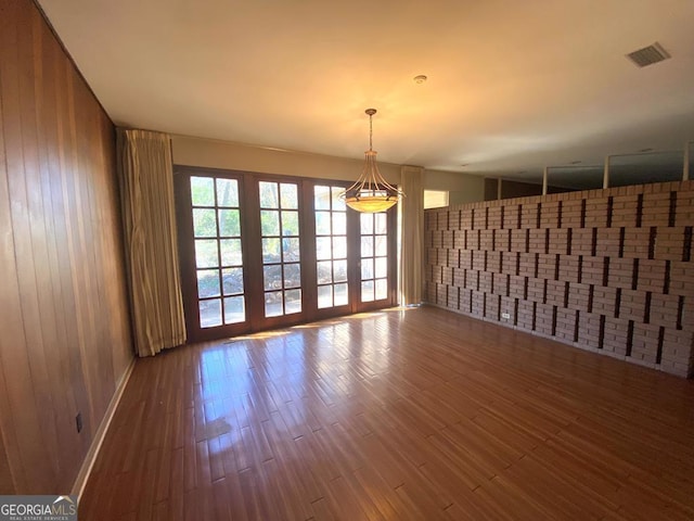 608 Pine Point Ct, Valdosta, GA 31602 - unfurnished room featuring visible vents, wooden walls, brick wall, and wood finished floors