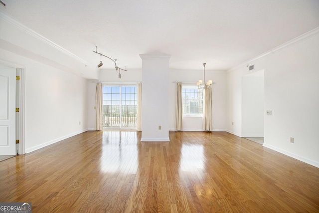 195 14th St NE Ph 306, Atlanta, GA 30309 - unfurnished living room featuring a chandelier, crown molding, light wood finished floors, baseboards, and track lighting