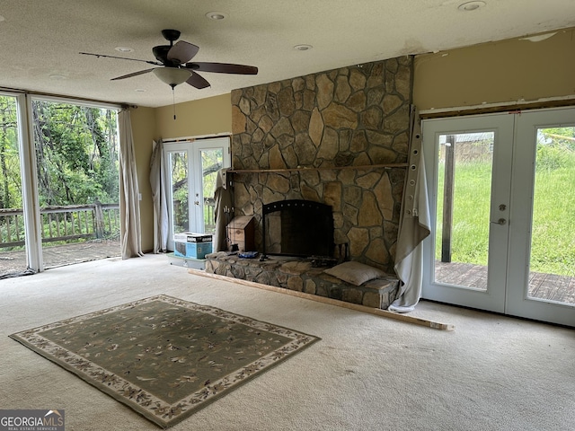 78 Ramblin Rose Ln, Rabun Gap, GA 30568 - unfurnished living room featuring french doors, carpet flooring, a textured ceiling, a ceiling fan, and a fireplace