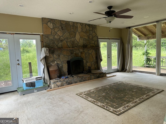 78 Ramblin Rose Ln, Rabun Gap, GA 30568 - unfurnished living room featuring carpet floors, french doors, a ceiling fan, a fireplace, and a textured ceiling