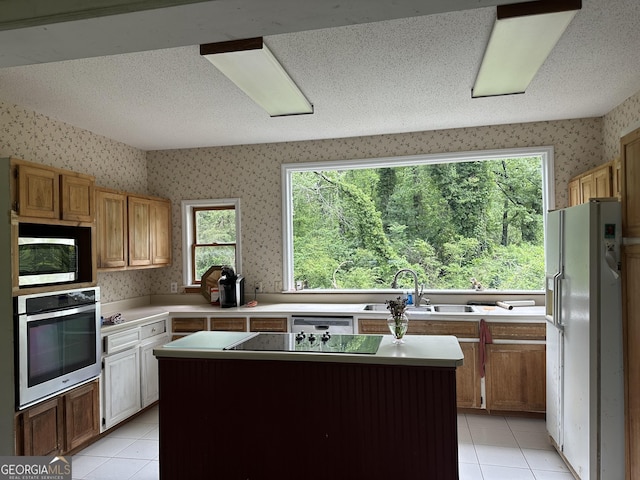 78 Ramblin Rose Ln, Rabun Gap, GA 30568 - kitchen featuring stainless steel appliances, a sink, wallpapered walls, light tile patterned floors, and light countertops