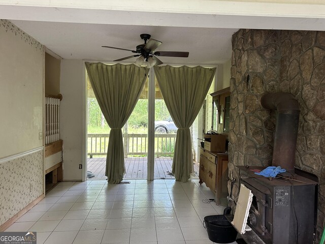 78 Ramblin Rose Ln, Rabun Gap, GA 30568 - living room featuring a wood stove, a ceiling fan, light tile patterned floors, baseboards, and wallpapered walls