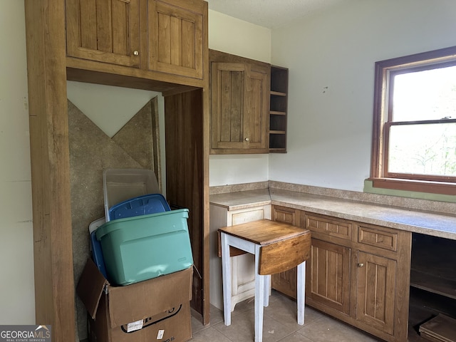 78 Ramblin Rose Ln, Rabun Gap, GA 30568 - kitchen with light tile patterned floors, open shelves, light countertops, and brown cabinets
