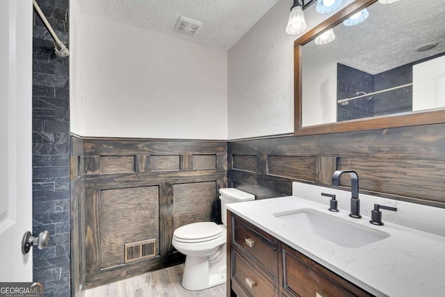 2285 Bascomb Carmel Rd, Woodstock, GA 30189 - bathroom featuring a textured ceiling, vanity, wood finished floors, a shower, and wainscoting