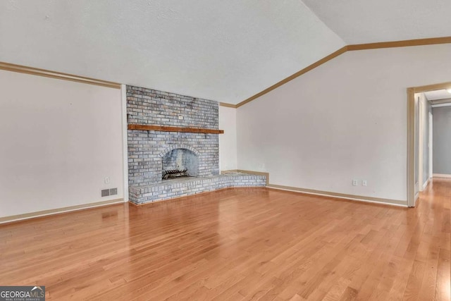2285 Bascomb Carmel Rd, Woodstock, GA 30189 - unfurnished living room featuring crown molding, vaulted ceiling, wood finished floors, and a brick fireplace