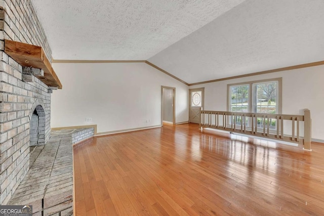 2285 Bascomb Carmel Rd, Woodstock, GA 30189 - unfurnished living room featuring crown molding, wood-type flooring, lofted ceiling, a textured ceiling, and a fireplace