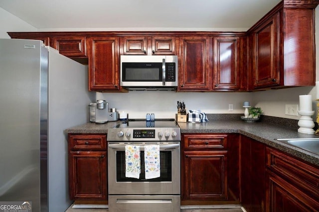 413 W I Pkwy, Dallas, GA 30132 - kitchen featuring reddish brown cabinets, dark countertops, and appliances with stainless steel finishes