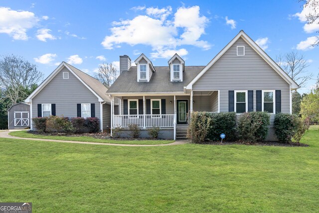 cape cod house featuring covered porch, a shed, a chimney, and a front lawn