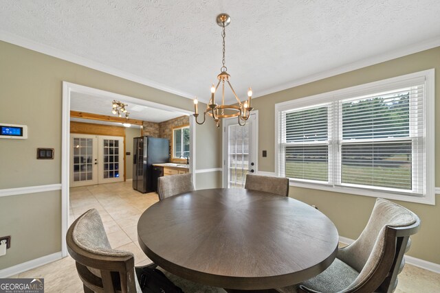 dining area with a chandelier, crown molding, baseboards, light tile patterned floors, and a textured ceiling