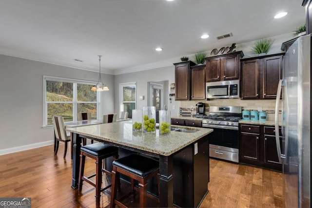 3475 Summerlin Pkwy, Lithia Springs, GA 30122 - kitchen featuring light stone countertops, visible vents, wood finished floors, and appliances with stainless steel finishes