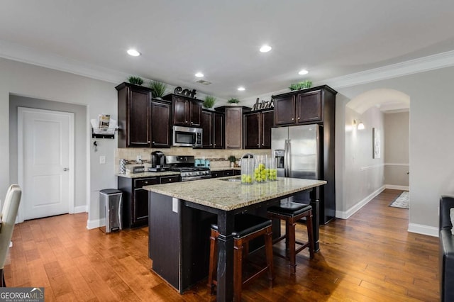 3475 Summerlin Pkwy, Lithia Springs, GA 30122 - kitchen with dark wood-style flooring, stainless steel appliances, backsplash, arched walkways, and dark brown cabinetry
