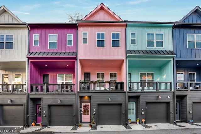 townhome / multi-family property with board and batten siding, a standing seam roof, a garage, and metal roof