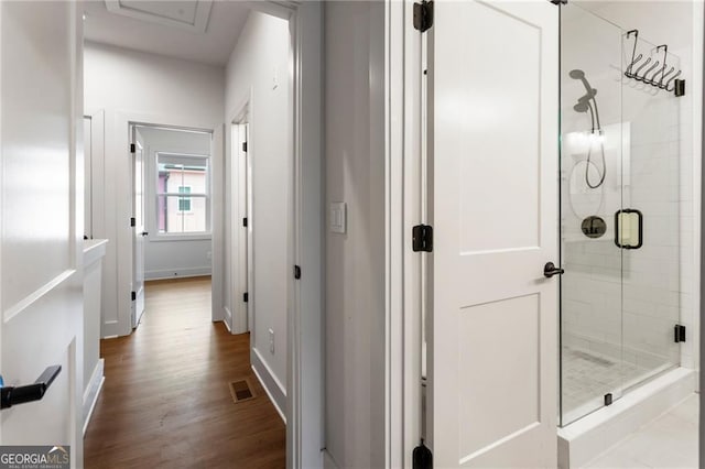 hallway with dark wood-type flooring, baseboards, and visible vents