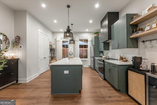 kitchen with light countertops, stainless steel range with electric cooktop, a center island with sink, backsplash, and beverage cooler