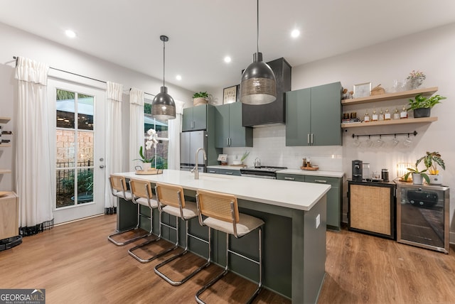 kitchen with light wood-type flooring, a kitchen island with sink, light countertops, a sink, and stainless steel appliances