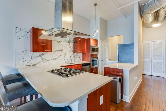 3820 Roswell Rd NE Unit 902, Atlanta, GA 30342 - kitchen featuring backsplash, a breakfast bar area, appliances with stainless steel finishes, a peninsula, and island exhaust hood