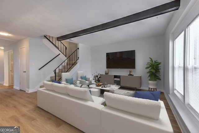 living room with light wood finished floors, baseboards, beam ceiling, and stairway