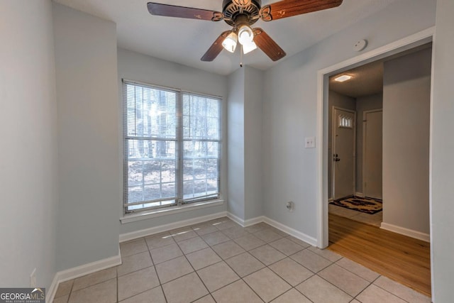 empty room with baseboards, a ceiling fan, and light tile patterned floors