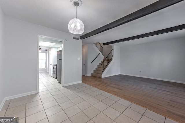 unfurnished room with light tile patterned floors, visible vents, beamed ceiling, stairway, and a notable chandelier
