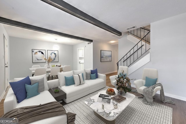 living area with beam ceiling, stairway, wood finished floors, baseboards, and visible vents