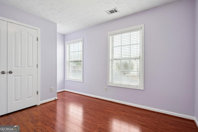 810 Abbotts Mill Ct Unit 83, Duluth, GA 30097 - unfurnished bedroom featuring a closet, wood finished floors, a textured ceiling, baseboards, and visible vents