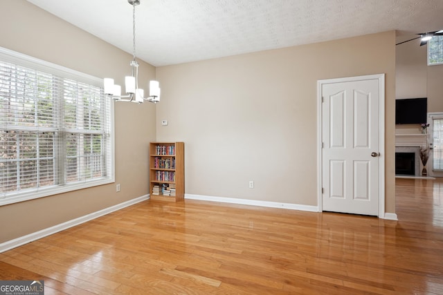 810 Abbotts Mill Ct Unit 83, Duluth, GA 30097 - unfurnished dining area with an inviting chandelier, baseboards, a textured ceiling, light wood finished floors, and a fireplace