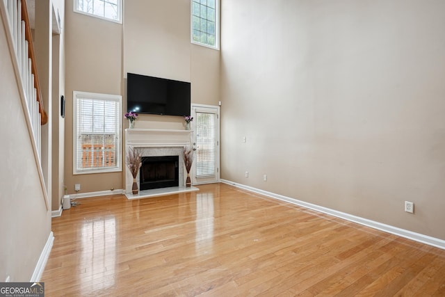 810 Abbotts Mill Ct Unit 83, Duluth, GA 30097 - unfurnished living room featuring a high ceiling, a high end fireplace, light wood-style floors, and a healthy amount of sunlight