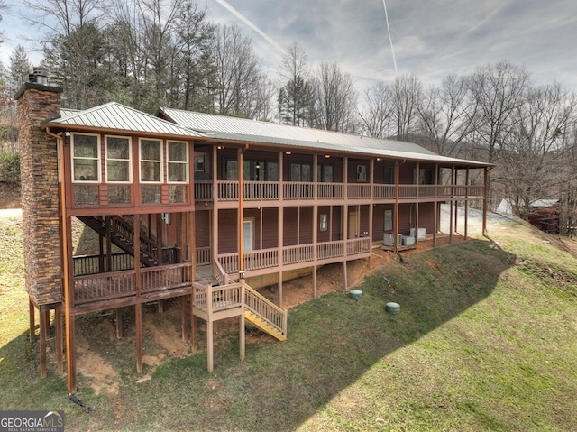 rear view of property with a yard, stairway, a chimney, and metal roof