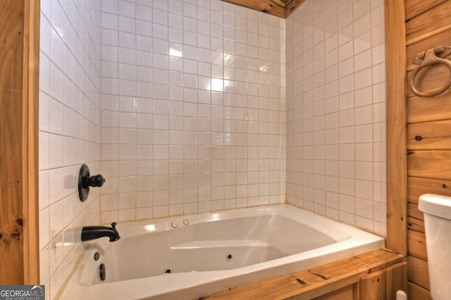 bathroom with tile walls, toilet, and a jetted tub