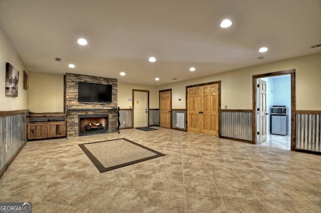 unfurnished living room with visible vents, a stone fireplace, recessed lighting, and a wainscoted wall