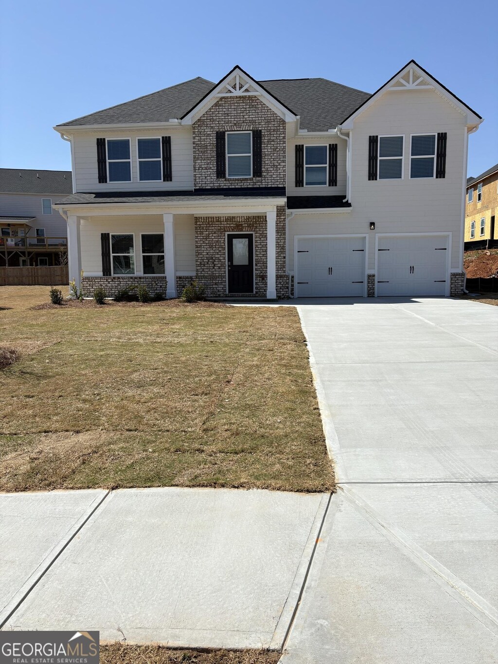 view of front facade with stone siding, concrete driveway, a garage, a front lawn, and a porch