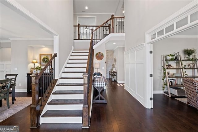 entrance foyer featuring crown molding, stairway, a high ceiling, wood finished floors, and baseboards