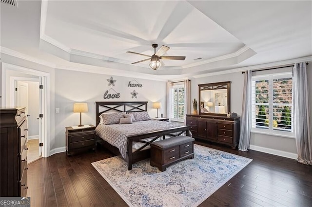 bedroom featuring dark wood-style floors, crown molding, baseboards, and a raised ceiling