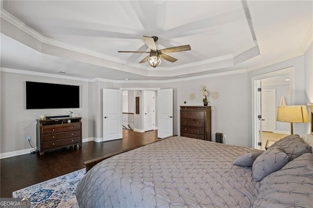 bedroom featuring baseboards, a tray ceiling, wood finished floors, and crown molding