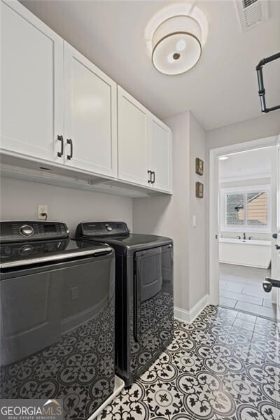 laundry room featuring washing machine and dryer, light tile patterned floors, baseboards, visible vents, and cabinet space