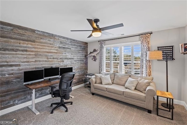 office area with wooden walls, ceiling fan, carpet, and an accent wall