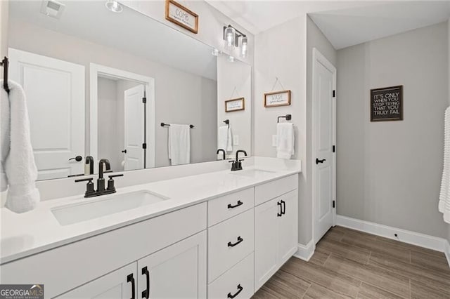 full bath with double vanity, a sink, and baseboards