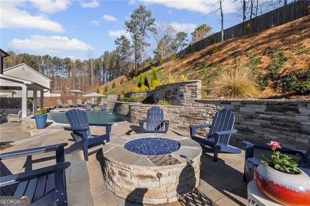 view of patio / terrace featuring an outdoor fire pit, a fenced backyard, and a fenced in pool