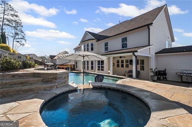 outdoor pool with grilling area, an in ground hot tub, and a patio area