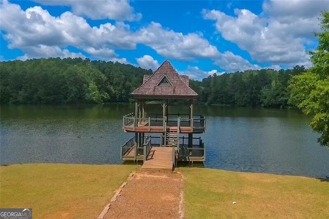 view of dock featuring a water view, a view of trees, and a yard