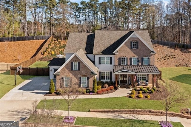 view of front of home with a front yard, fence, brick siding, and concrete driveway