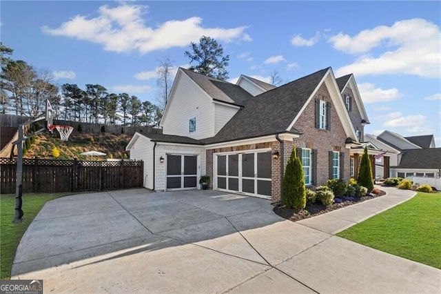 view of property exterior with fence, an attached garage, driveway, brick siding, and a yard
