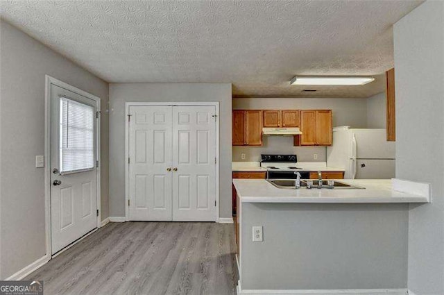 2892 Norfair Loop NE, Lithonia, GA 30038 - kitchen featuring under cabinet range hood, a sink, freestanding refrigerator, brown cabinetry, and range with electric cooktop