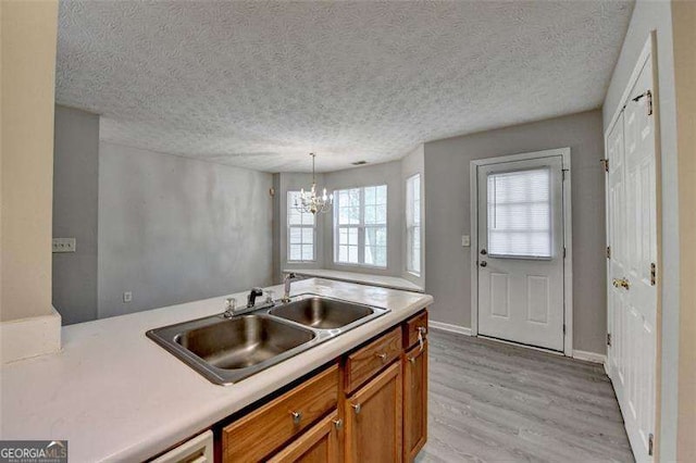 2892 Norfair Loop NE, Lithonia, GA 30038 - kitchen with light countertops, a sink, a chandelier, light wood finished floors, and brown cabinets