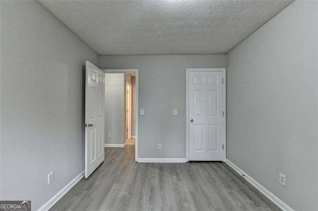 2892 Norfair Loop NE, Lithonia, GA 30038 - unfurnished bedroom featuring a textured ceiling, baseboards, and wood finished floors